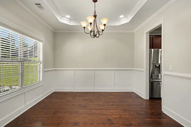 Dining room with wainscoting, a tray ceiling and a chandelier