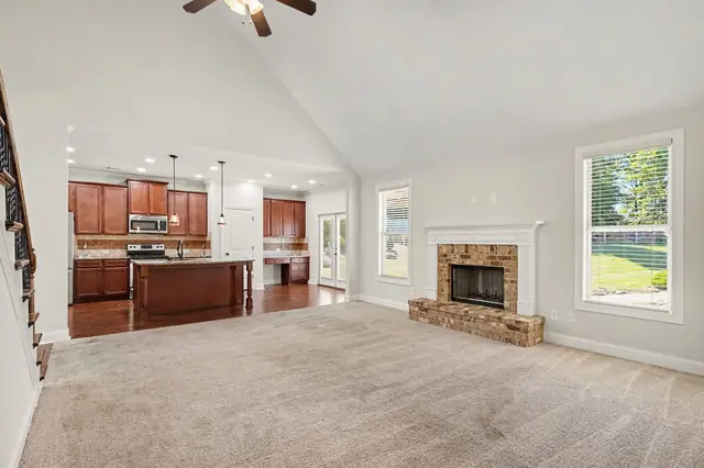 Family room with a stone fireplace, open to the kitchen