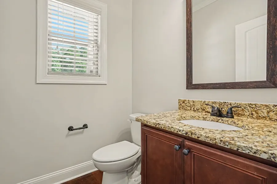 Half bath with a granite vanity and framed mirror
