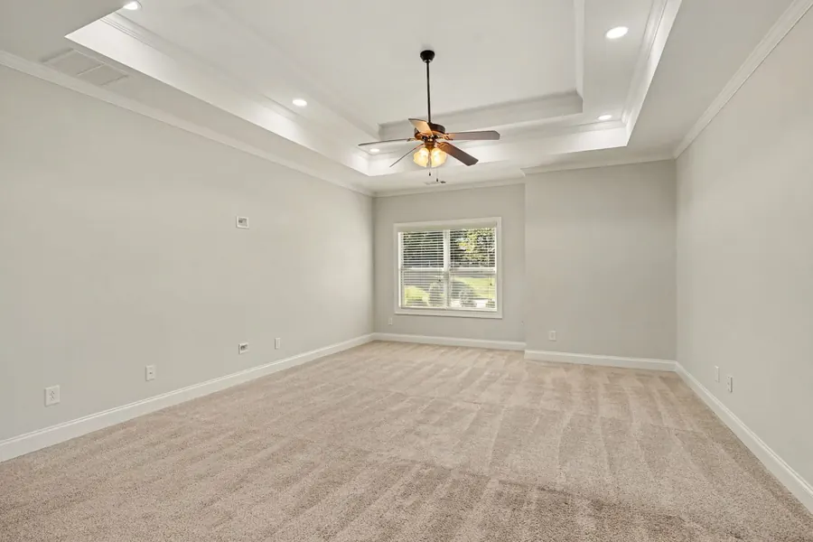 Large bedroom with a tray ceiling and ceiling fan